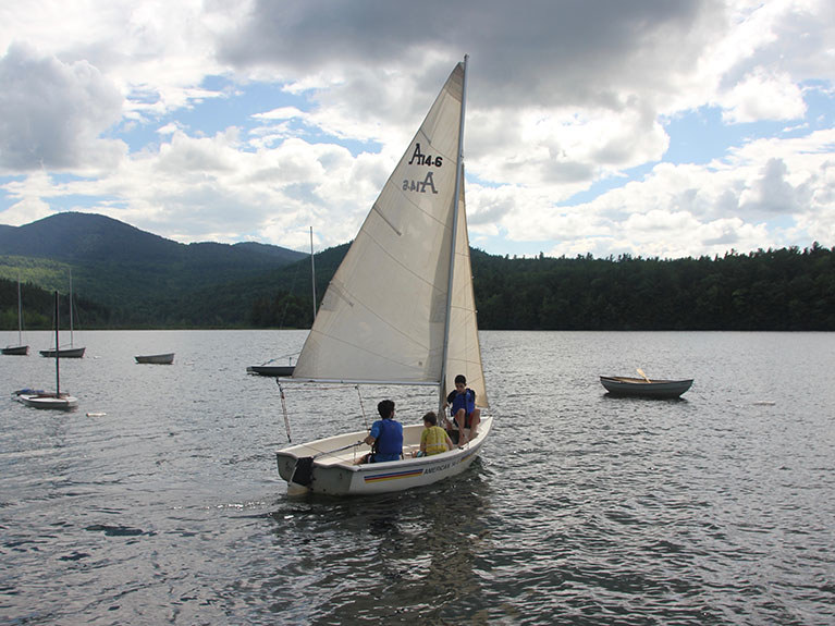 campers in sailboat on lake