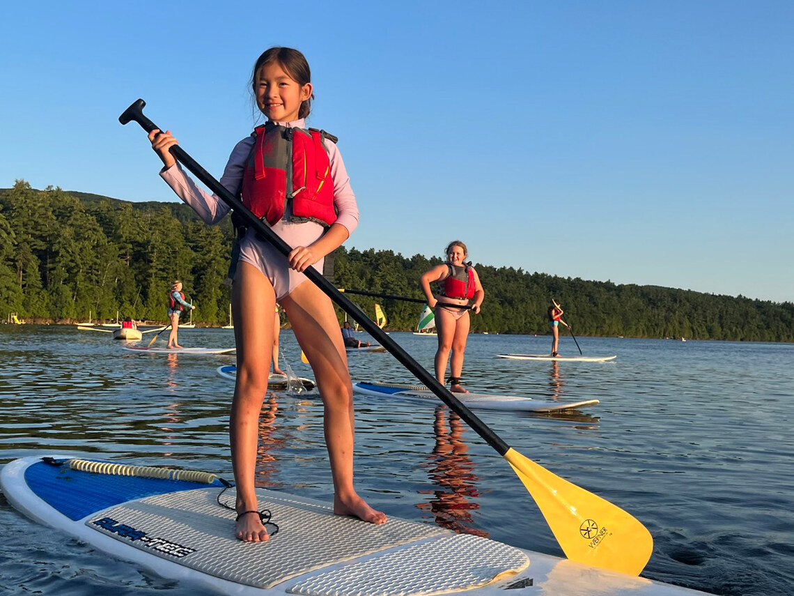 a group of campers standing on paddle boards