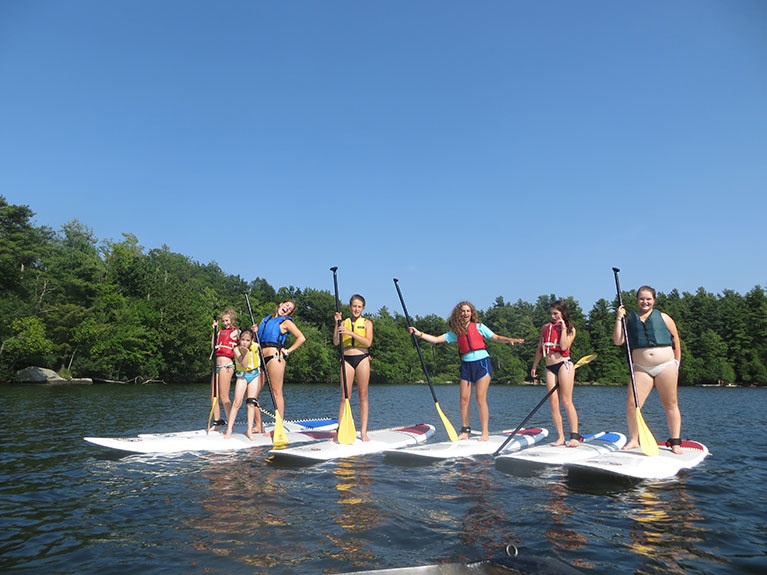 group of campers on paddle boards in lake