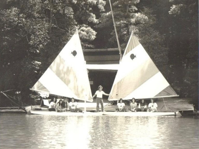 Black and white photograph of two sailboats bow to bow with a person standing between them