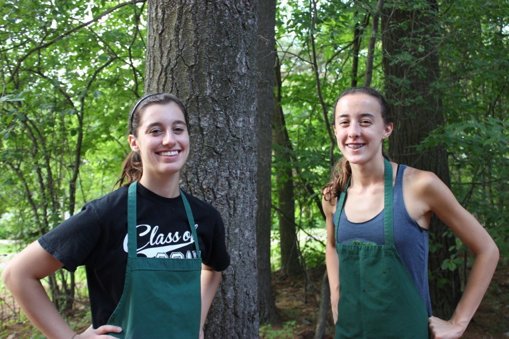 Two girls in aprons in woods smiling