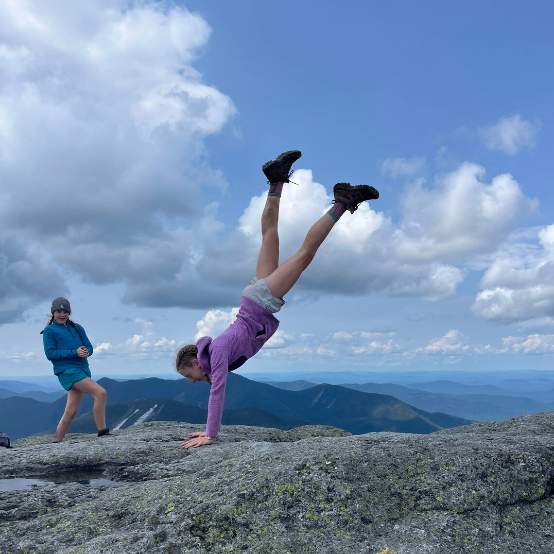 camper doing a handstand atop a mountain