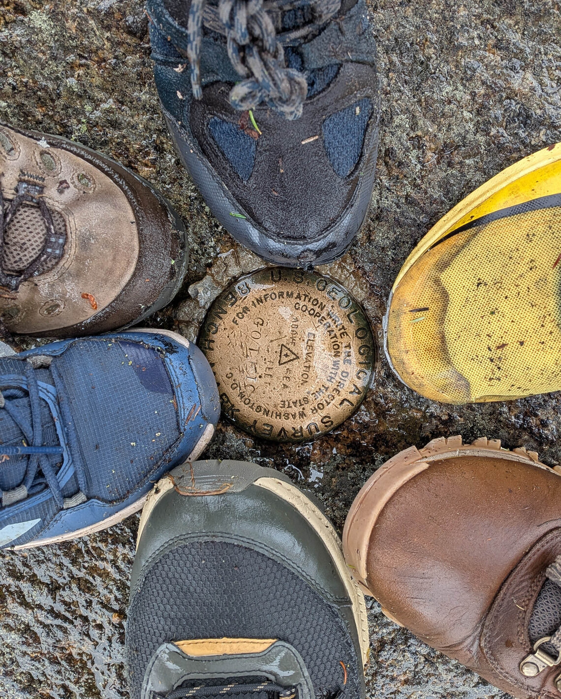 6 boots around a summit marker on an adirondack peak