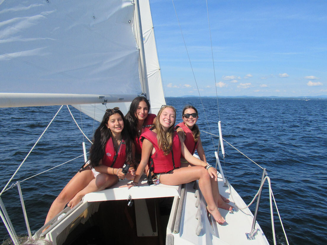 campers smiling on the bow of a large sailboat