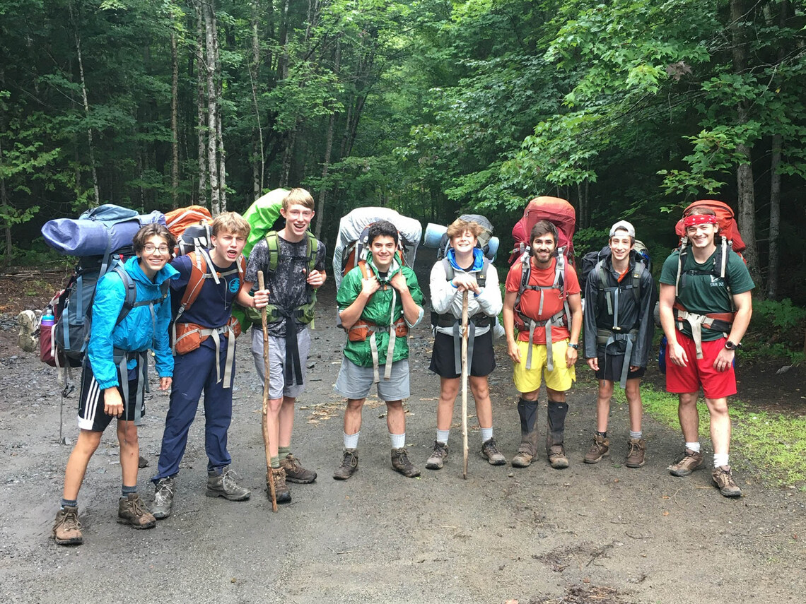 campers wearing framepacks and standing in the woods