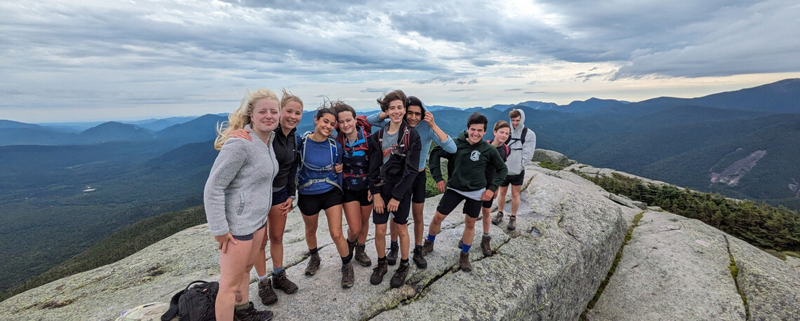 campers smiling on top of a windy mountain summit