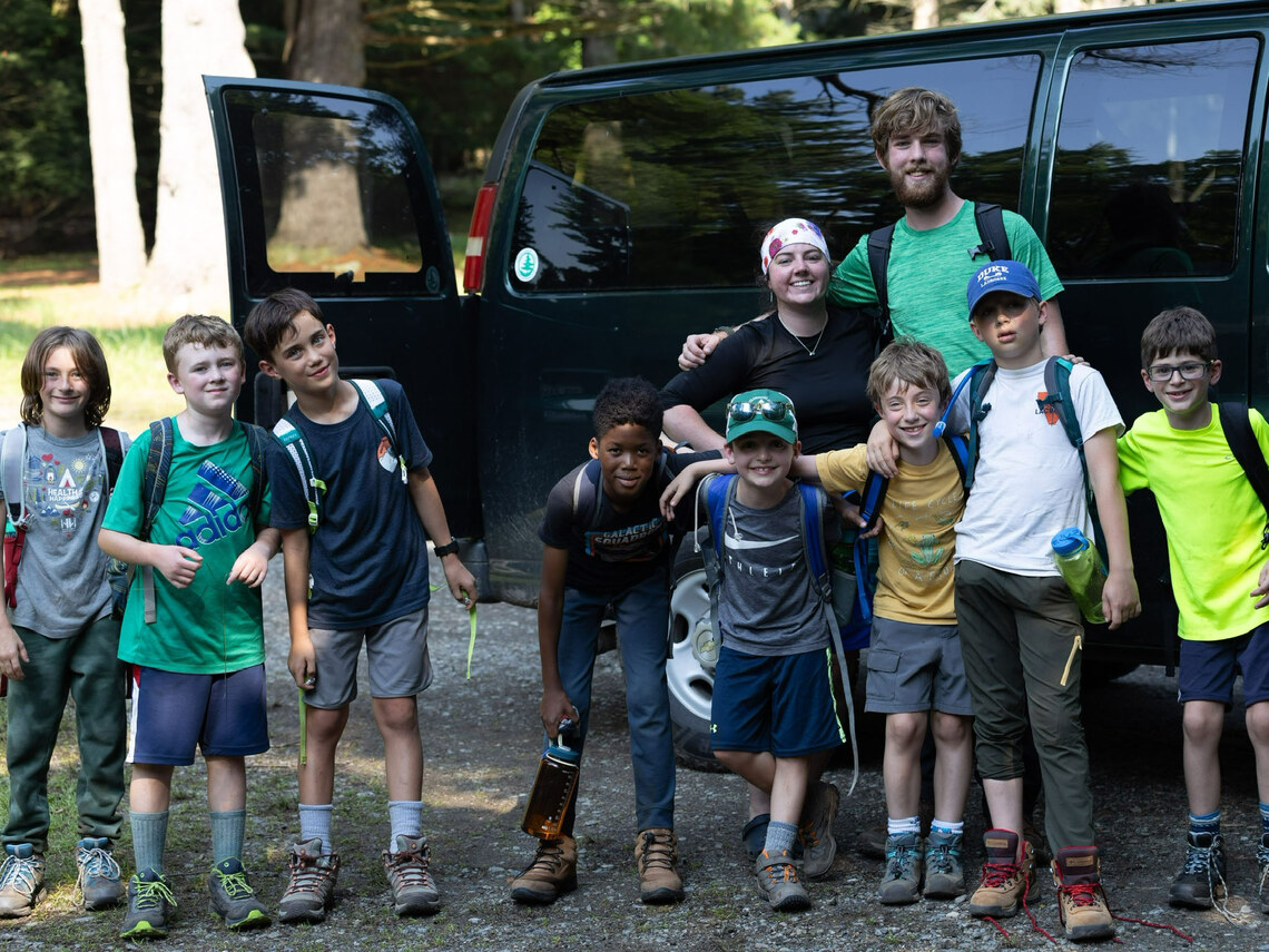 a group of campers and counselors standing in front of a van