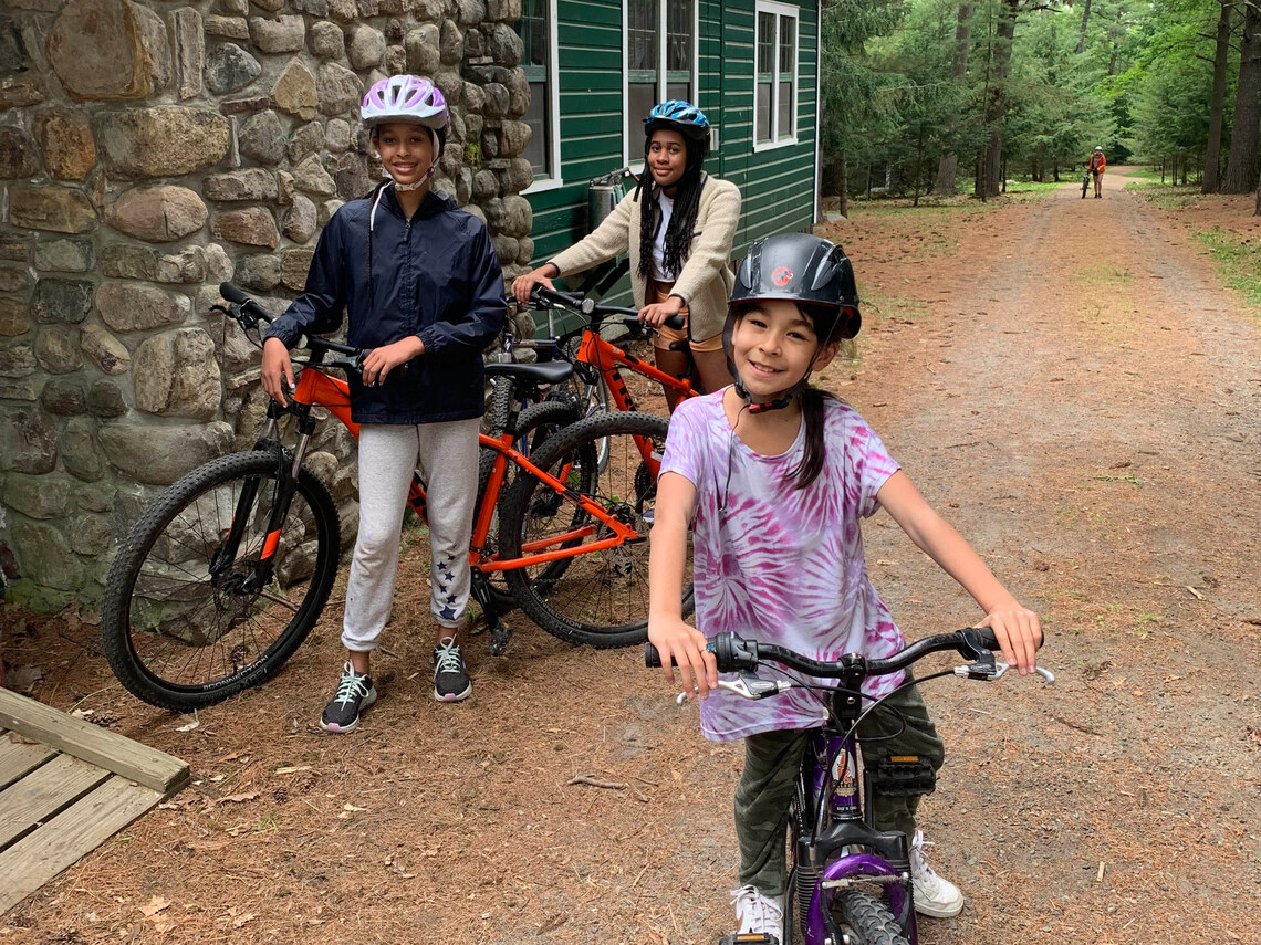 Three campers standing over their bikes and smiling