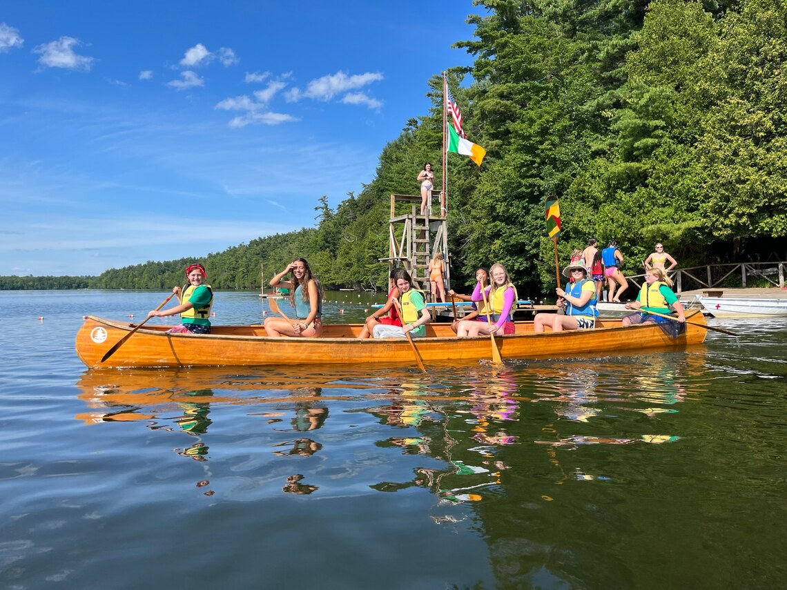A large group of campers paddling in a very large canoe