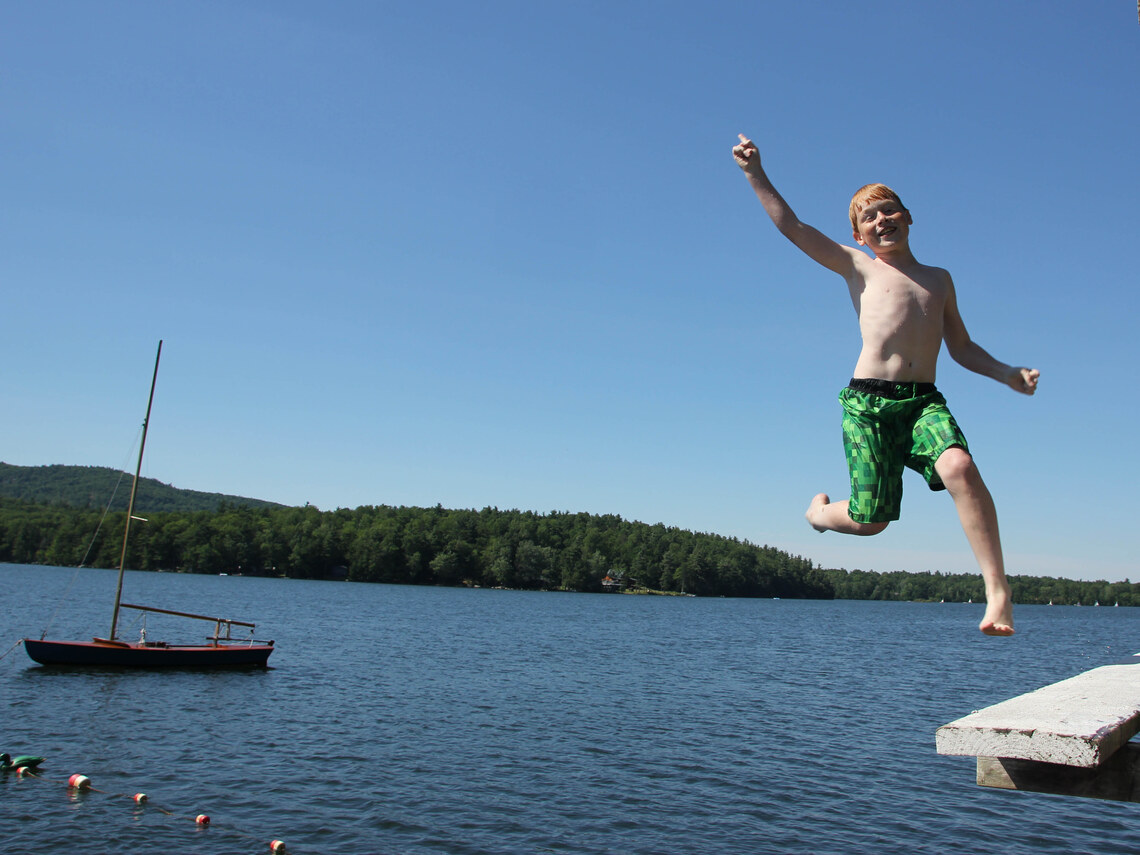 campers leaping off of a platform into a lake