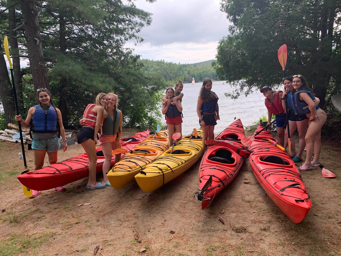 Campers smiling in front of their sea kayaks