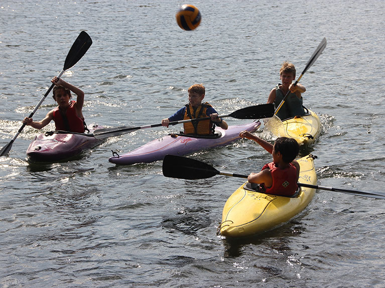 campers playing game in lake on kayaks