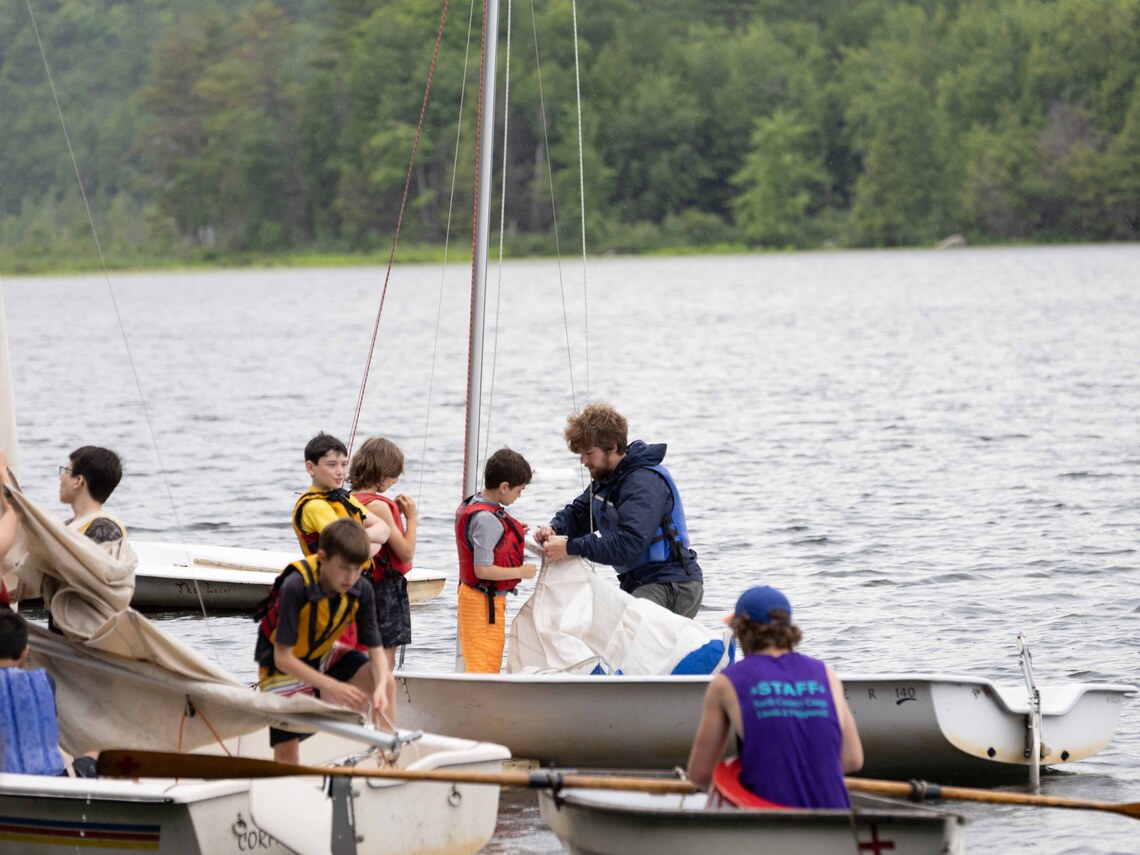 A counselor teaching a group of campers about the parts of a sailboat