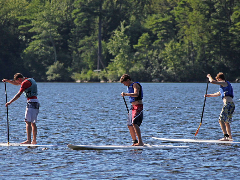 group of campers on paddle boards in lake