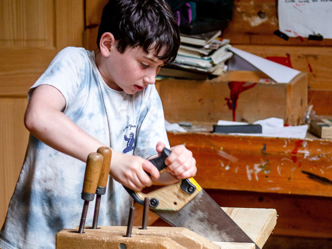 a boy sawing a piece of wood