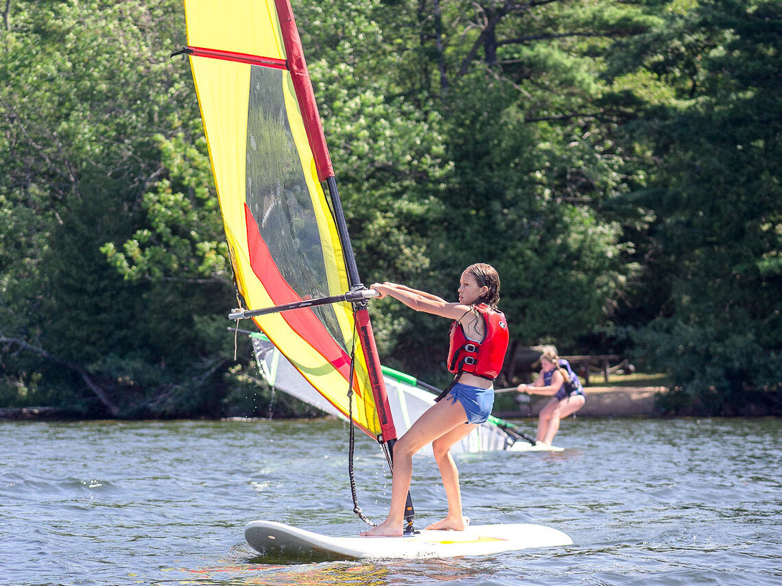 a group of campers windsurfing on a lake