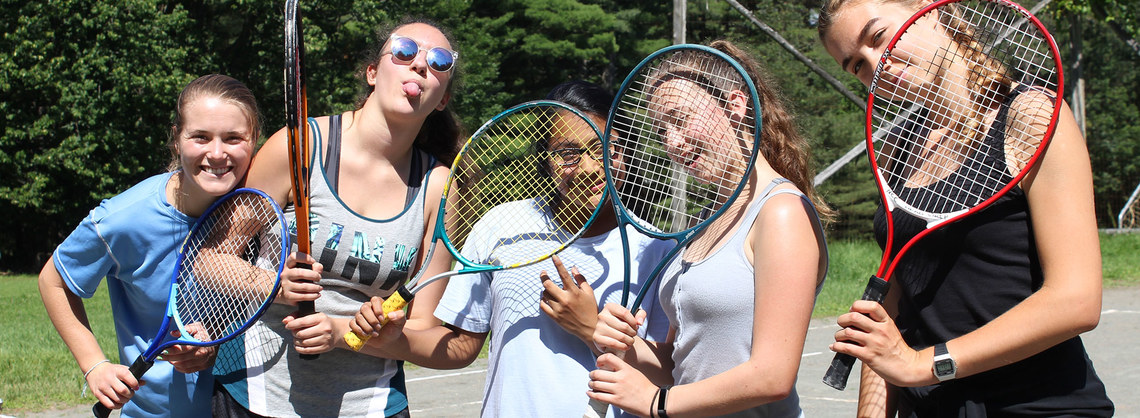 group of campers smiling with tennis rackets