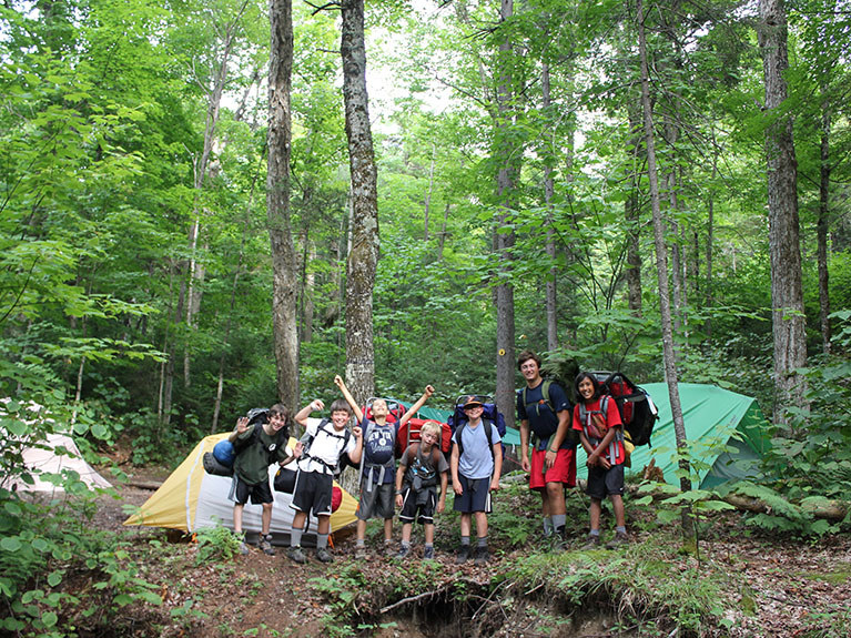 campers in front of camp site in woods