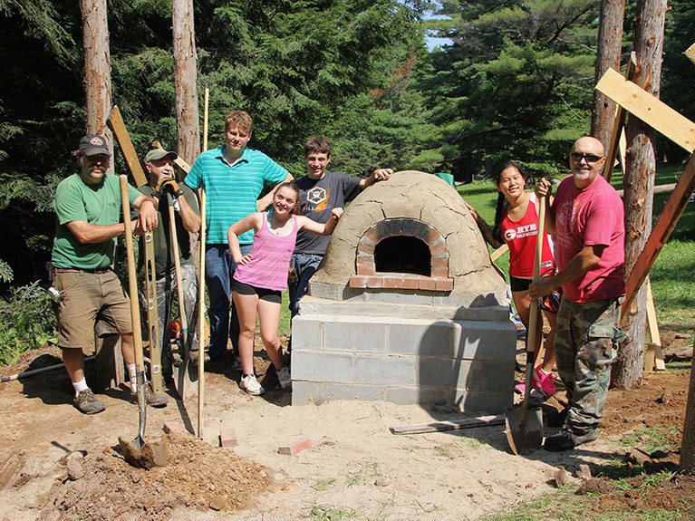 campers and instructor next to cob oven they built