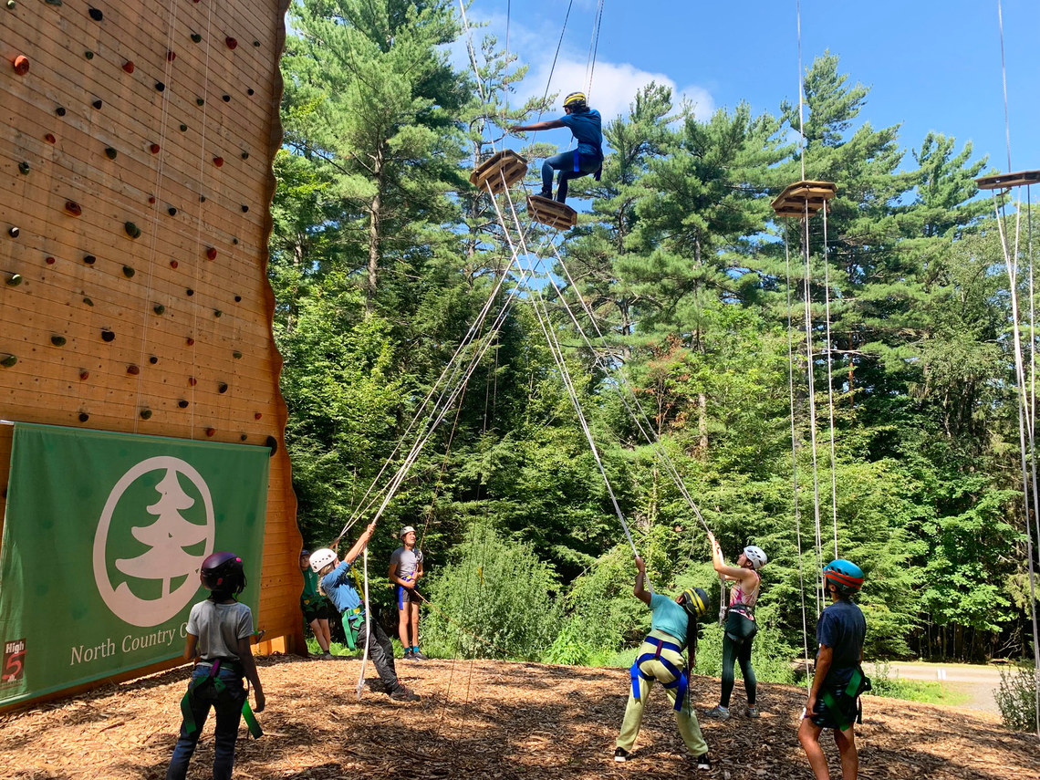 Campers working together to complete a ropes course element high in the air