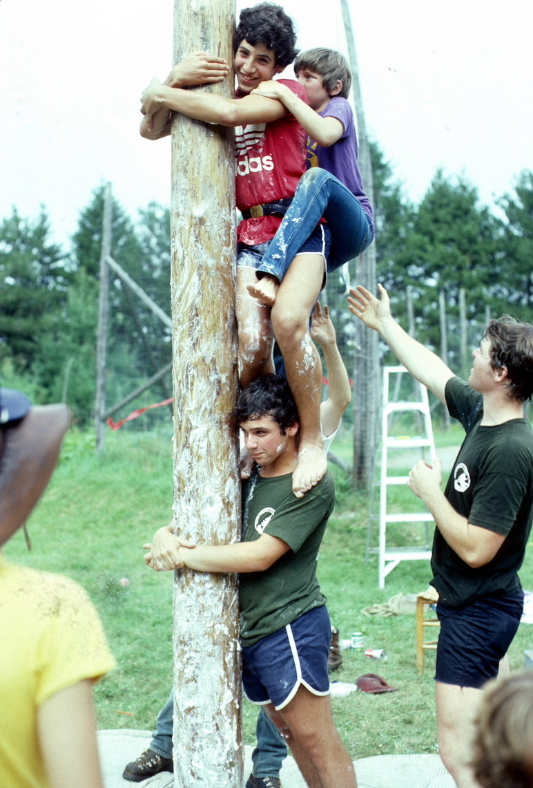 Lincoln campers using teamwork to climb a greased pole at midseason event in the 1980s