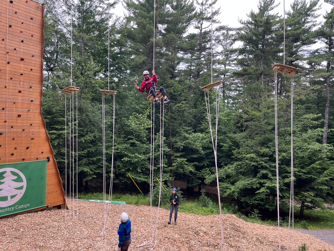 A group of people playing on new ropes course elements