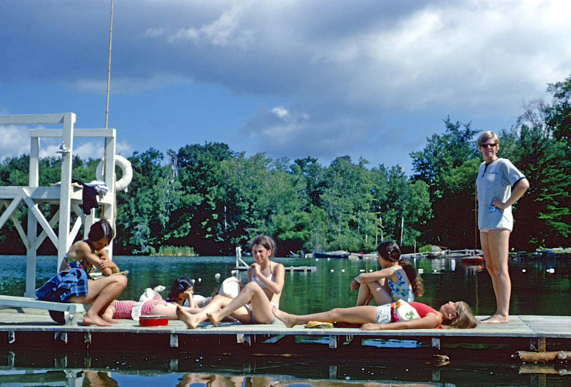 Campers and staff sitting on a dock over the water