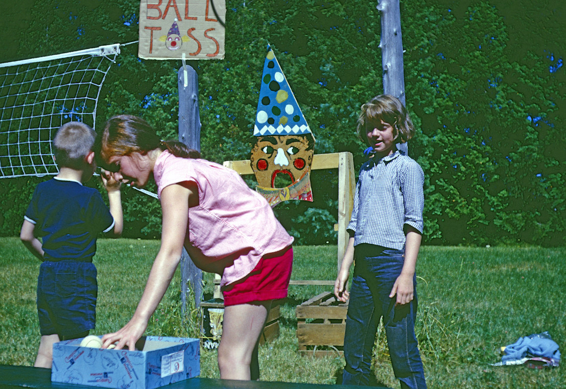 Campers playing a ball toss game into a cut out wooden clown head