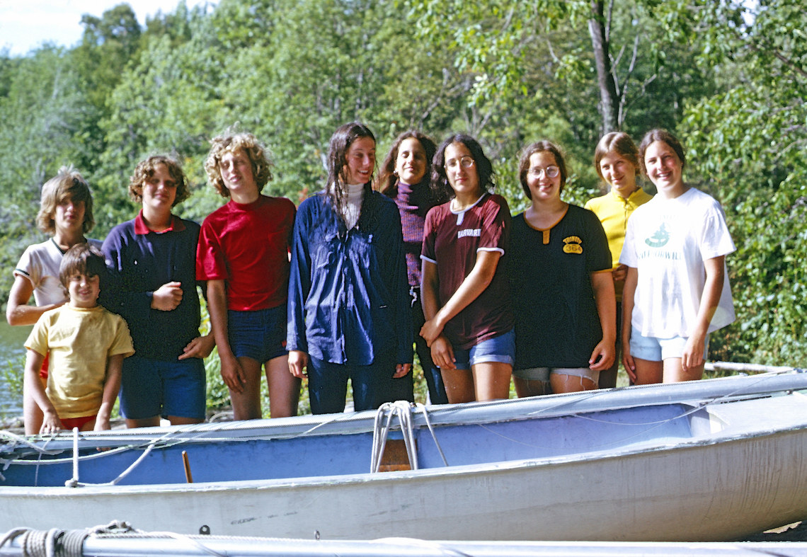 campers smiling behind a sailboat with its mast down