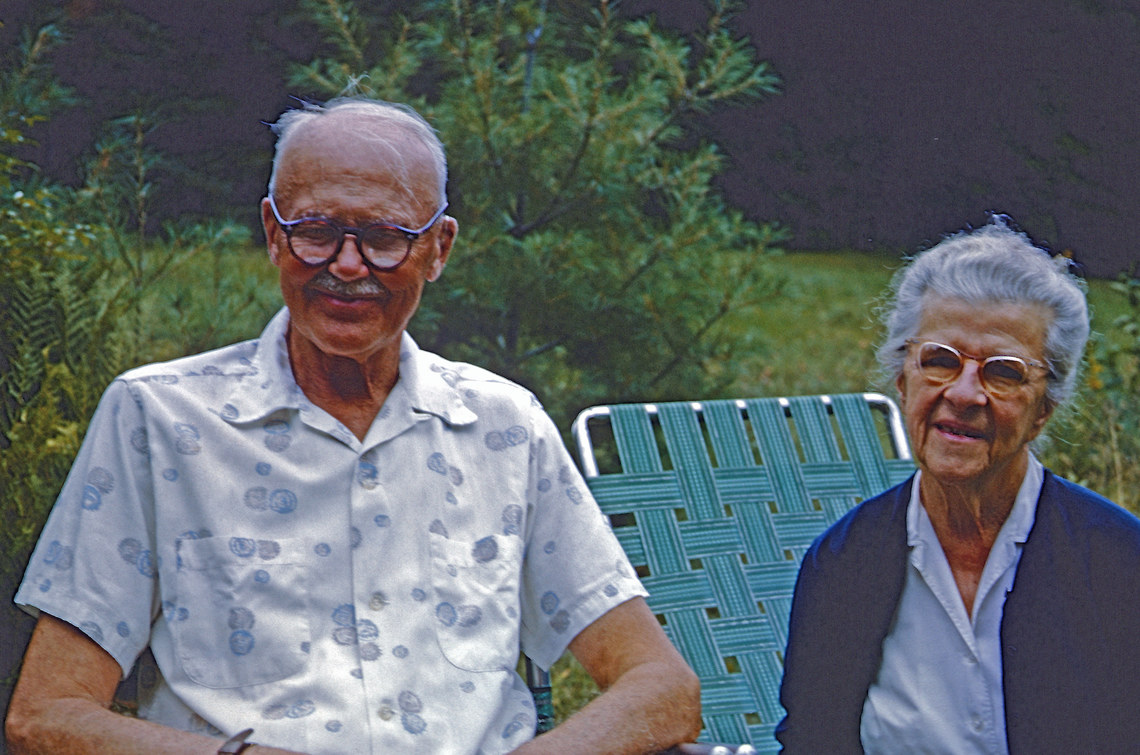 Two people with white hair and glasses sitting side by side in lawn chairs