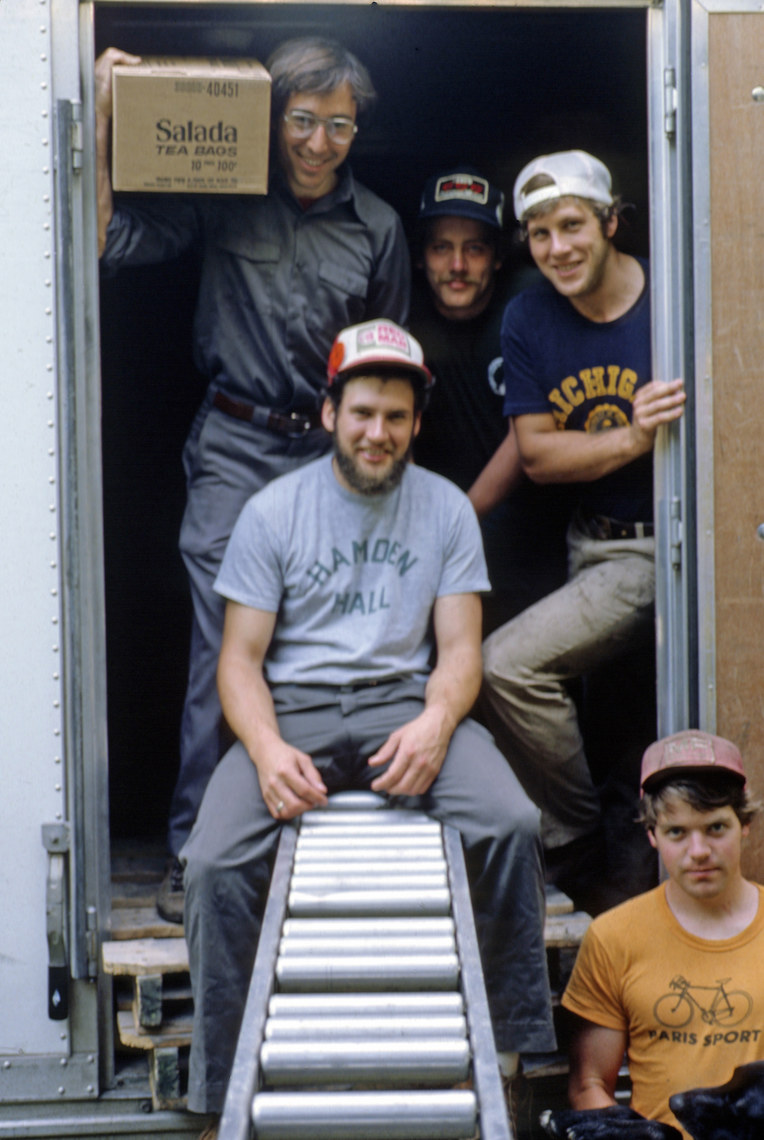 A group of men standing inside the door to a box truck